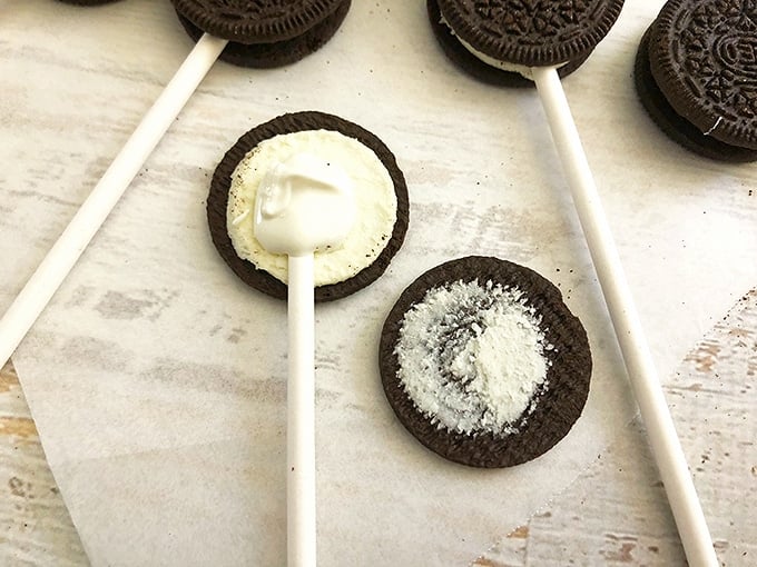 placing a lollipop stick on the Oreo filling to prepare for dipping in chocolate