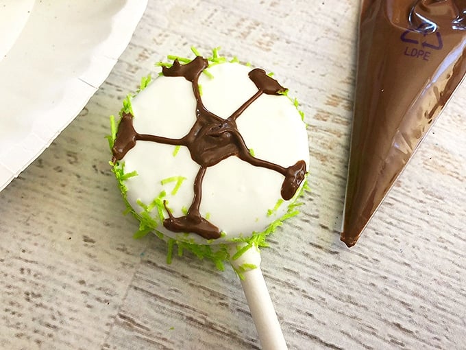 Soccer Oreo Pops covered in white chocolate and sprinkled with green sprinkles