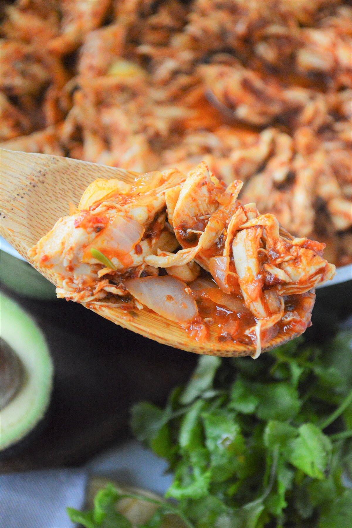 serving tinga de pollo from a skillet with a wooden spoon