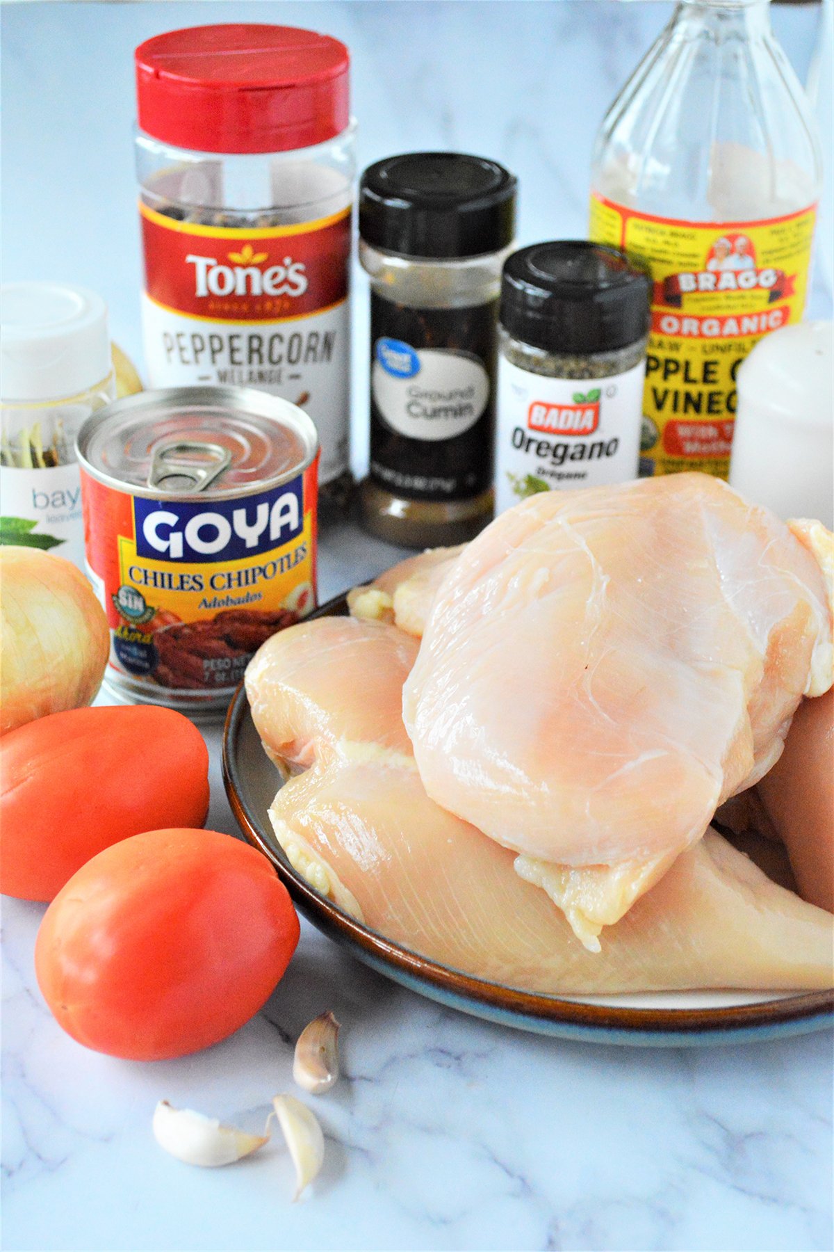 raw chicken breast, tomatoes, chipotle peppers in adobo sauce, apple cider vinegar, garlic cloves, cumin, oregano, bay leaves, and peppercorns