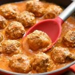 serving beef meatballs in tomato gravy with a spoon