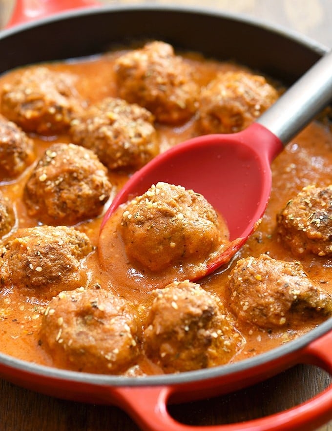 serving beef meatballs in tomato gravy with a spoon