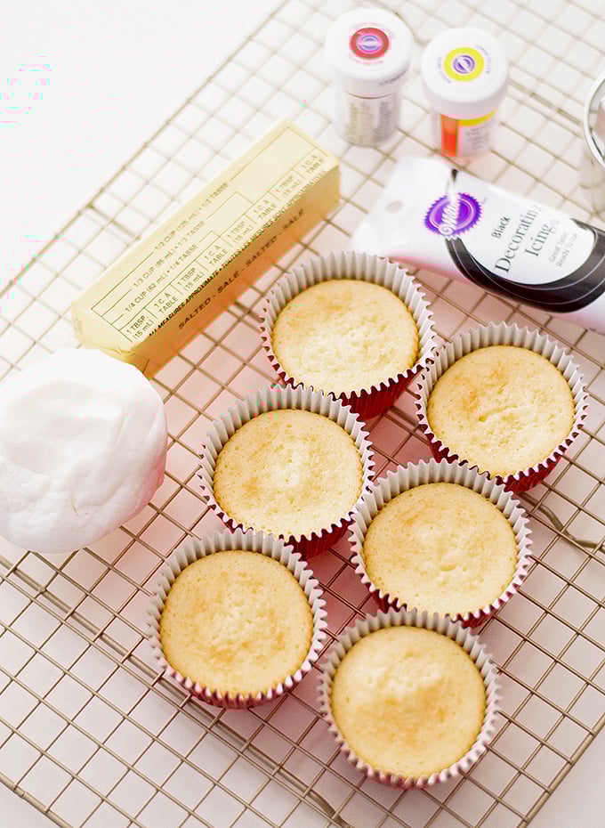 vanilla cupcakes, fondant, and food coloring on a wire rack