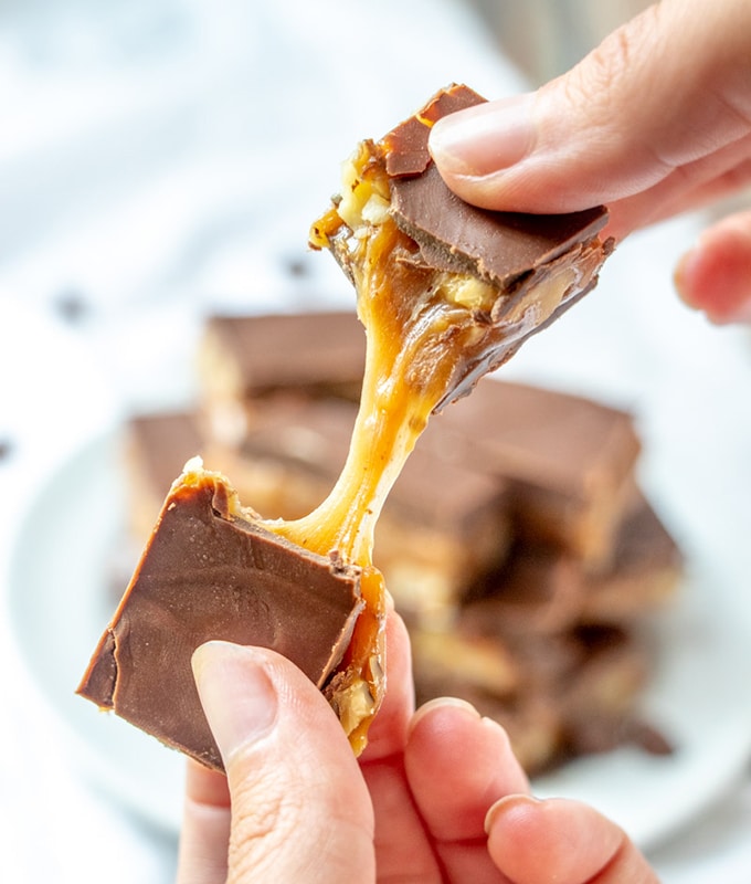 breaking a bar of gooey chocolate caramel candy bars with hands