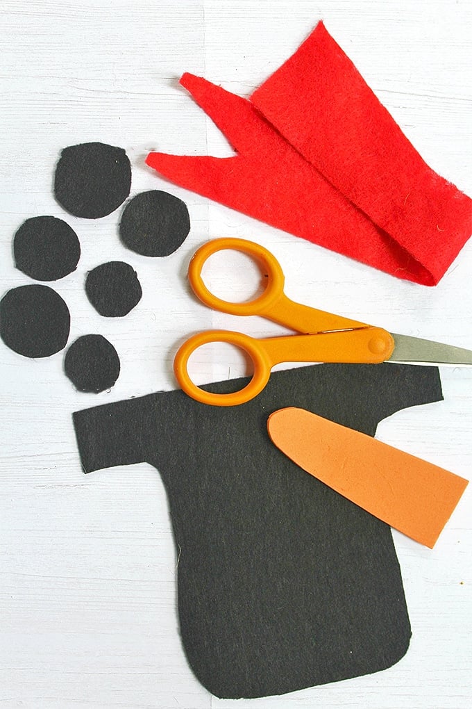 cut out black, red and orange felt and scissors to decorate snowman wood board decor