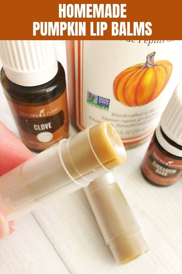holding homemade pumpkin lip balm with hands and essential oils on a white board