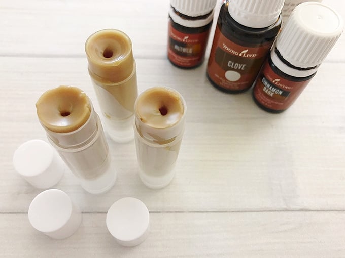 three tubes of homemade pumpkin chapsticks and essential oil bottles