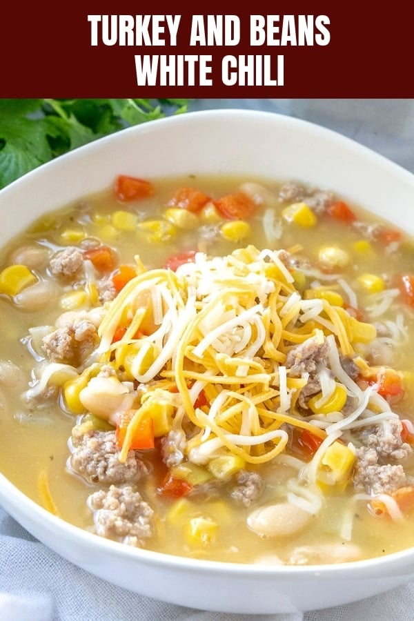 turkey and white bean chili topped with shredded cheese in a white bowl