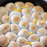Cheese Pull-Apart Bread Rolls baked in cast-iron skillet with glass of water in the background.