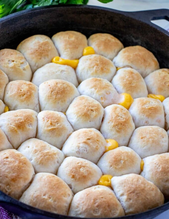 Cheese Pull-Apart Bread Rolls baked in cast-iron skillet with glass of water in the background.