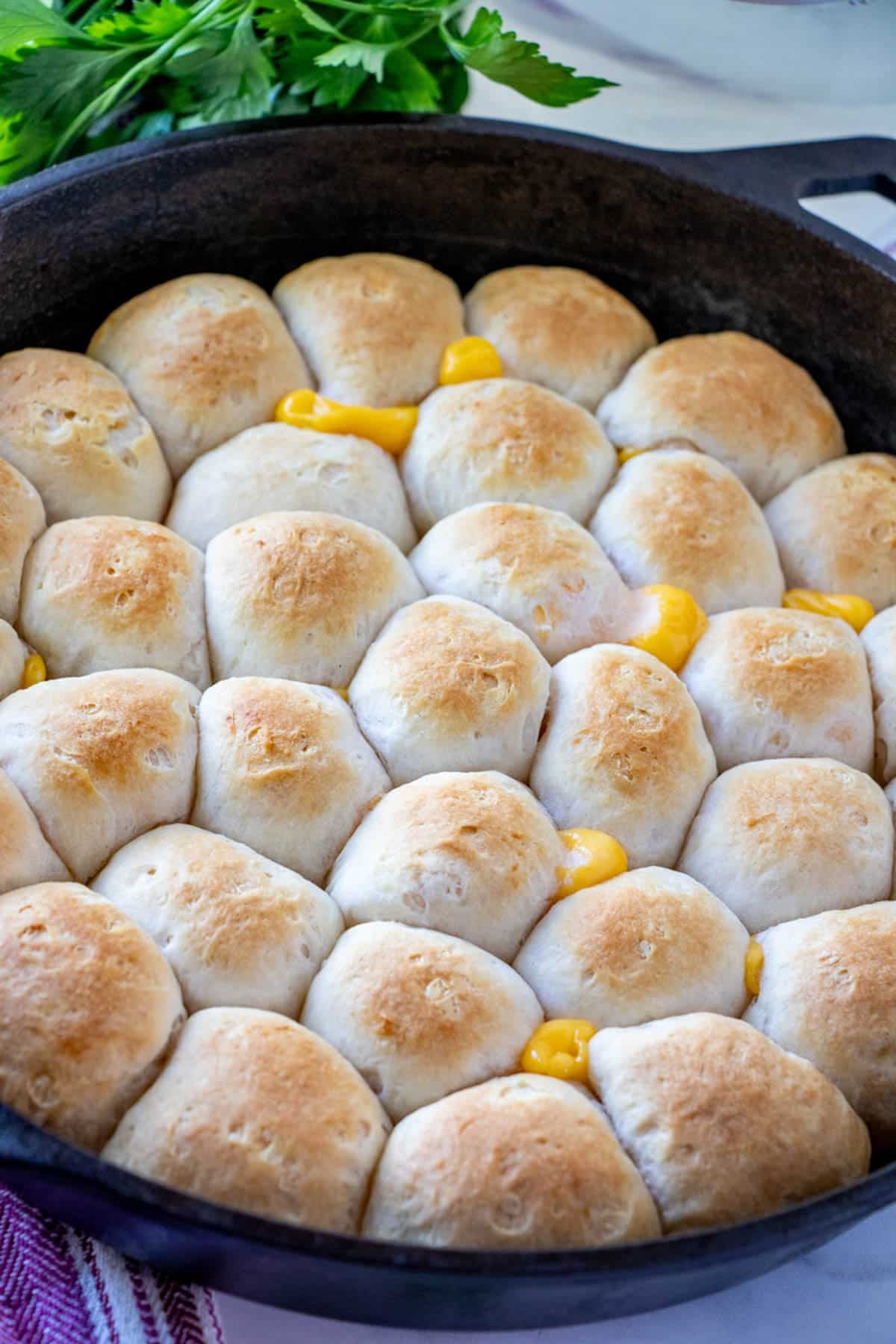 Cheese Pull-Apart Bread Rolls baked in cast-iron skillet with glass of water in the background.