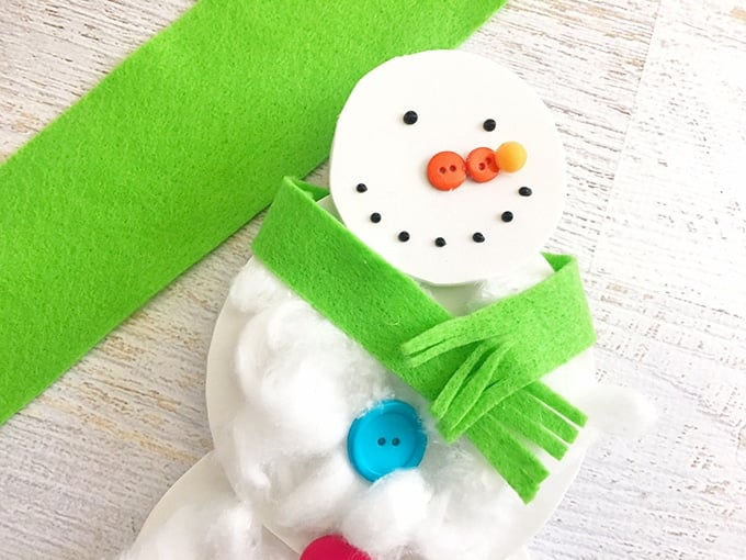 wrap and glue a green felt strip around snowman cotton ball craft to resemble a scarf