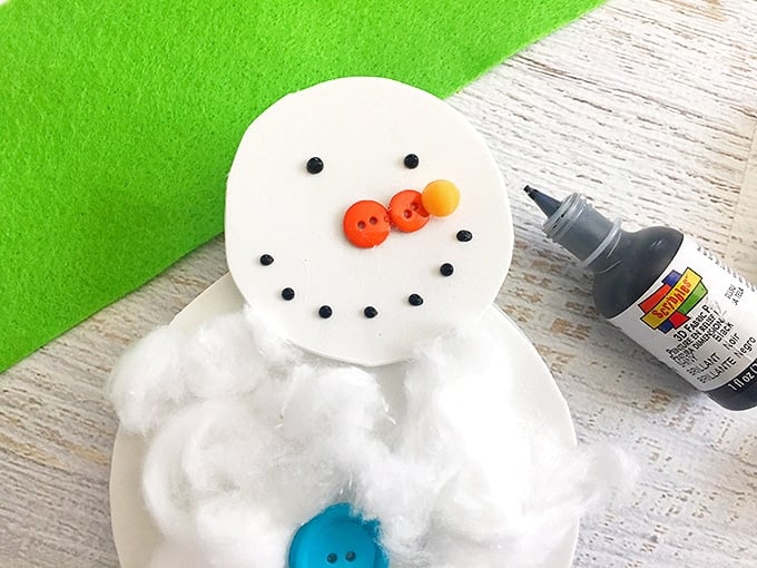 small orange buttons glued on snowman cotton ball craft to make the nose