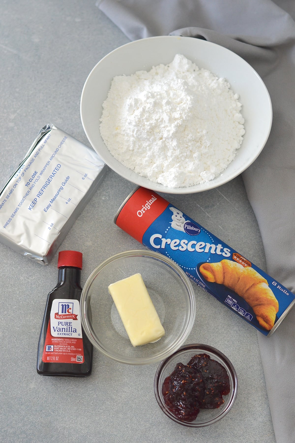refrigerated crescent rolls, butter, vanilla extract, cream cheese, jam, powdered sugar in a white bowl.