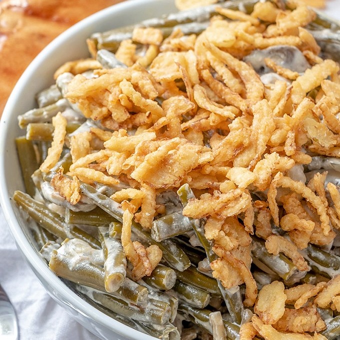 Slow Cooker Green Bean Casserole topped with french fried onions in a white serving bowl