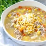 turkey and white bean chili topped with shredded cheese in a white bowl