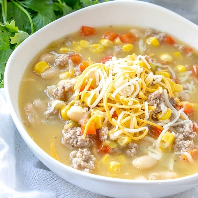 turkey and white bean chili topped with shredded cheese in a white bowl