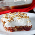 slice of cranberry jello salad with whipped topping on a white plate