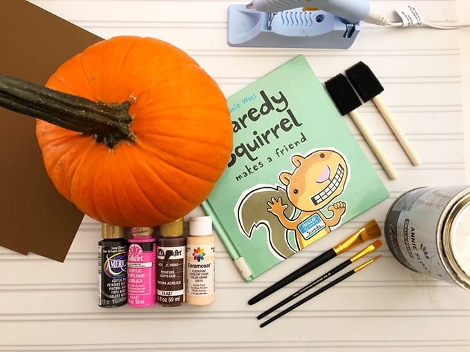 pumpkin, assorted craft paints, paintbrushes, hot glue gun, cardstock paper, and scaredy squirrel book