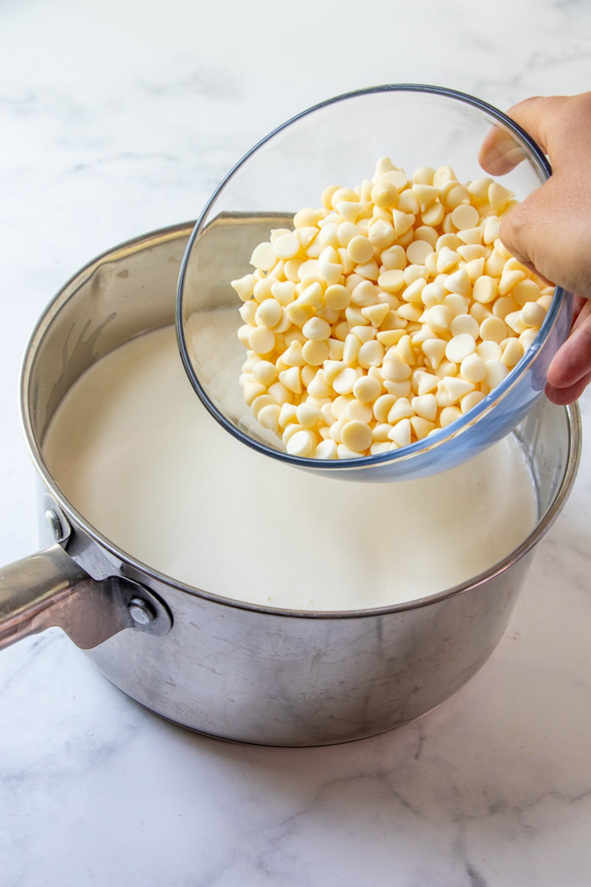 adding white chocolate chips to a saucepan or milk