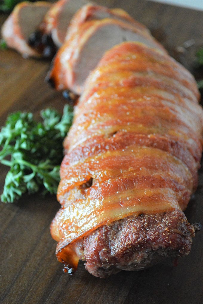 sliced bacon-wrapped pork tenderloin with brown sugar glaze on a cutting board