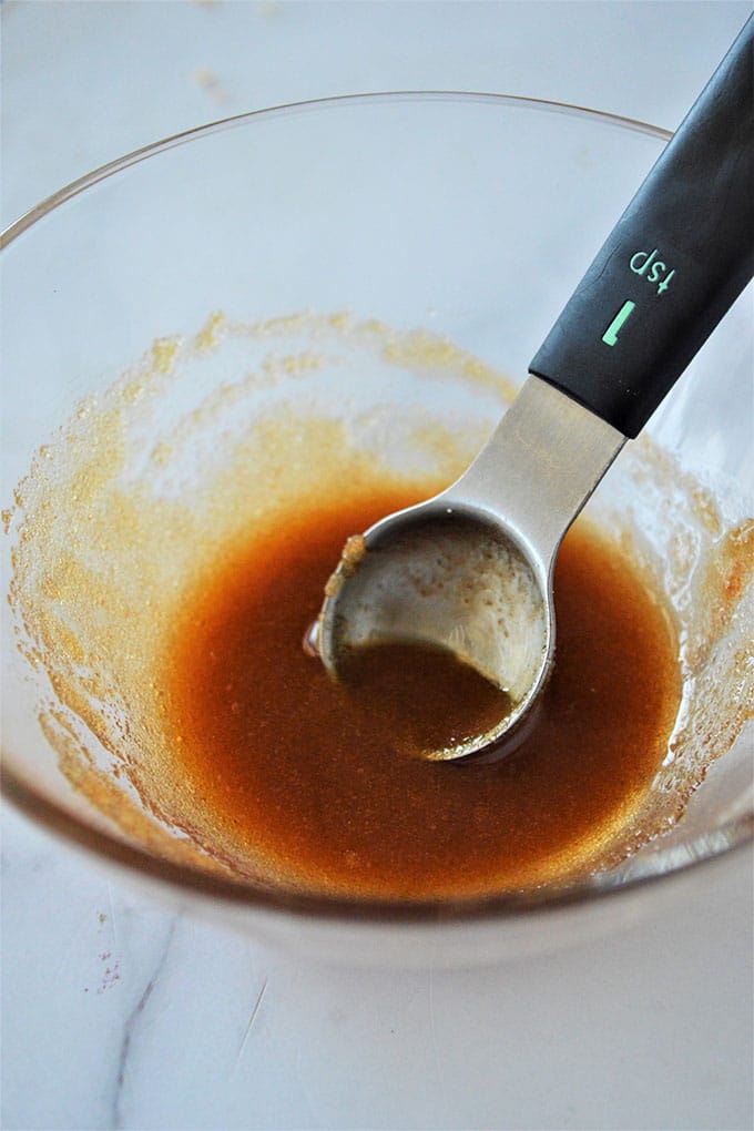 brown sugar and hot sauce mixture in a bowl with a measuring spoon