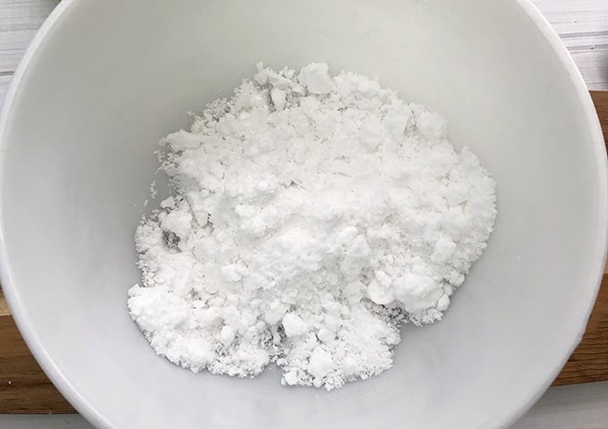 baking soda and citric acid in a white bowl to make christmas tree bath bombs