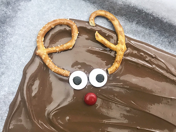 place candy eyes, pretzel halves and red M&M candy on layer of melted chocolate to make reindeer chocolate bark