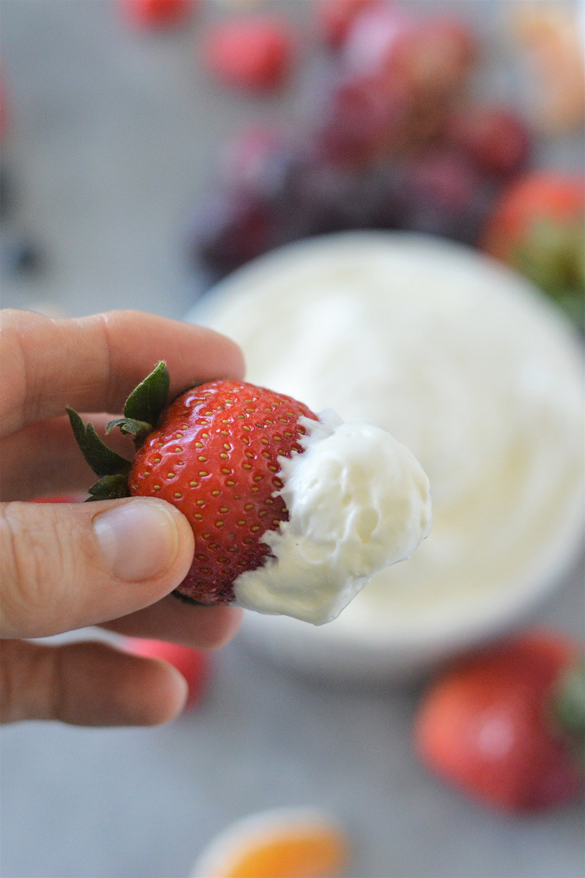 dipping strawberry in a bowl of cream cheese marshmallow dip