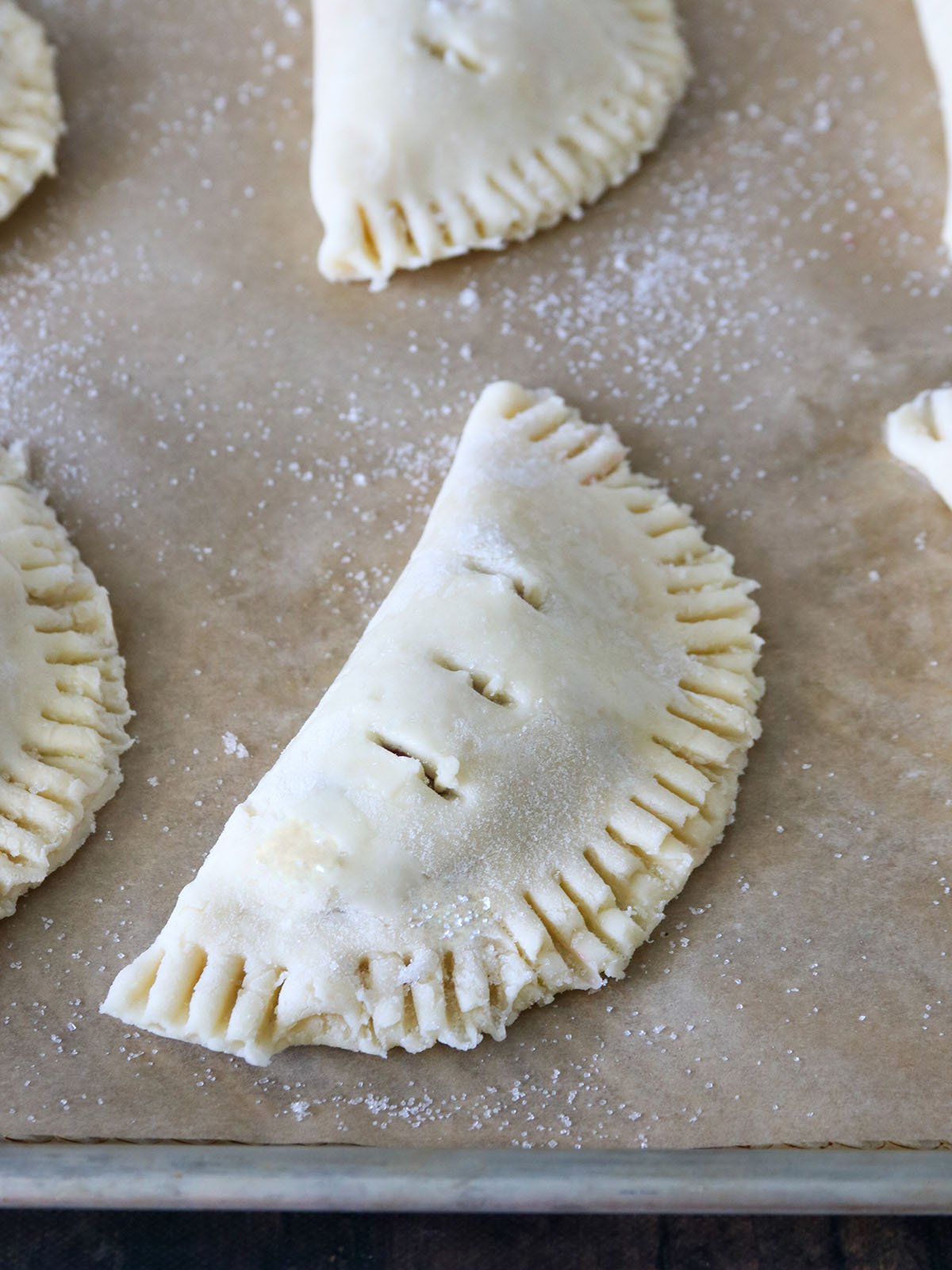 cherry hand pies on a parchment-lined baking sheet ready to bake