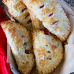 Homemade Cherry Hand Pies in a cloth-lined basket with fresh cherries on the side