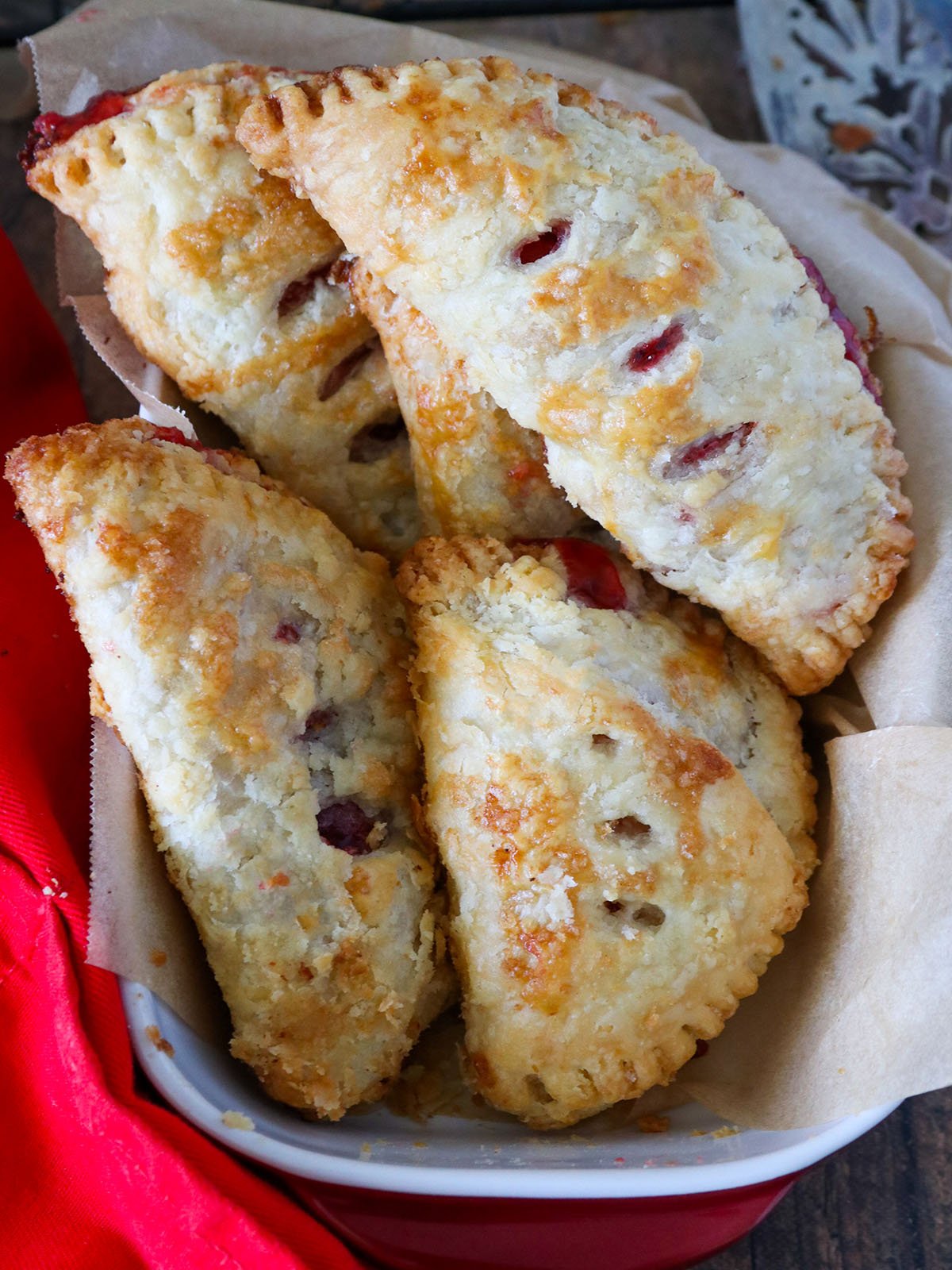 Homemade Cherry Hand Pies in a cloth-lined basket with fresh cherries on the side