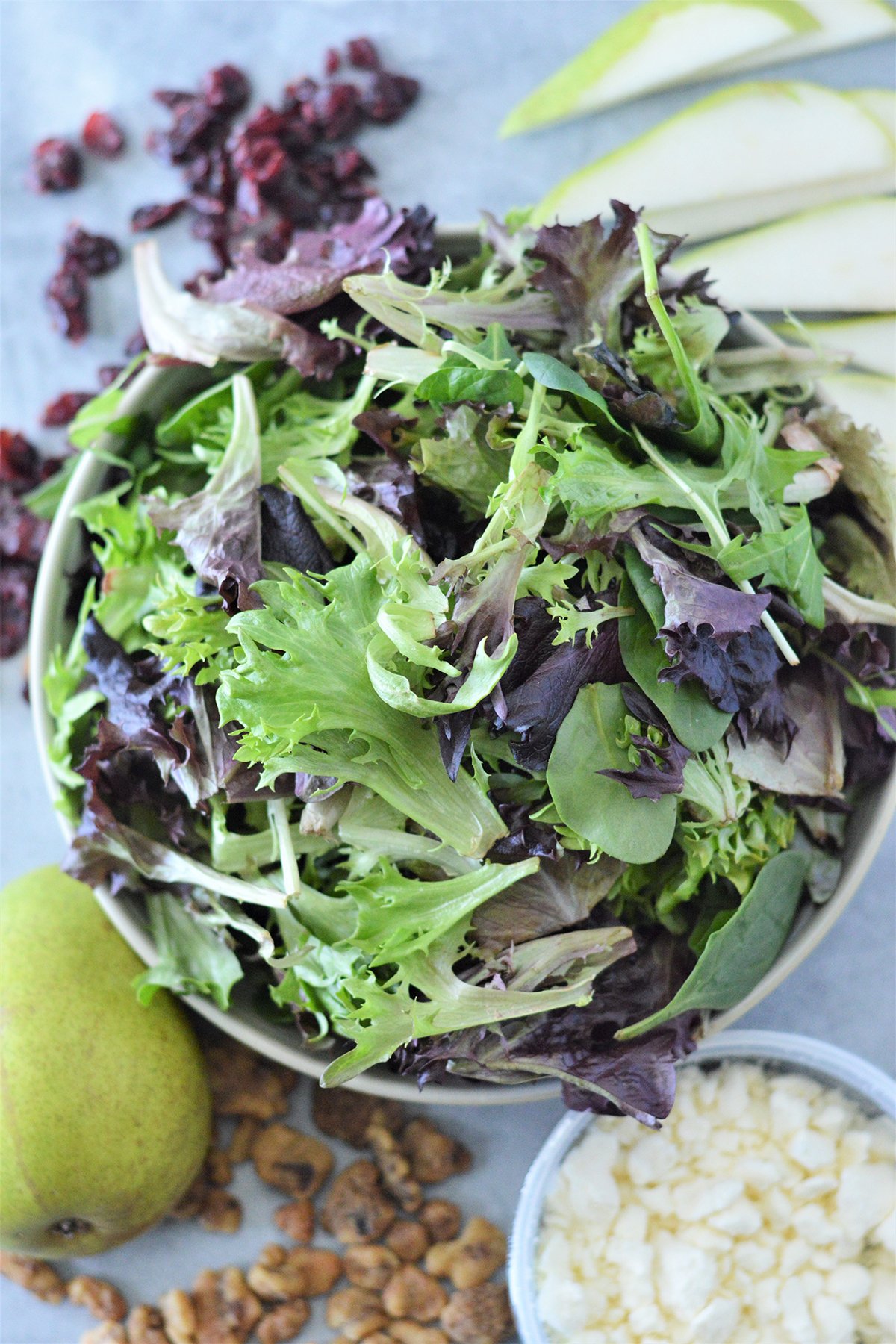 spring salad mix in a bowl, pear, candied walnuts, feta cheese, dried cranberries