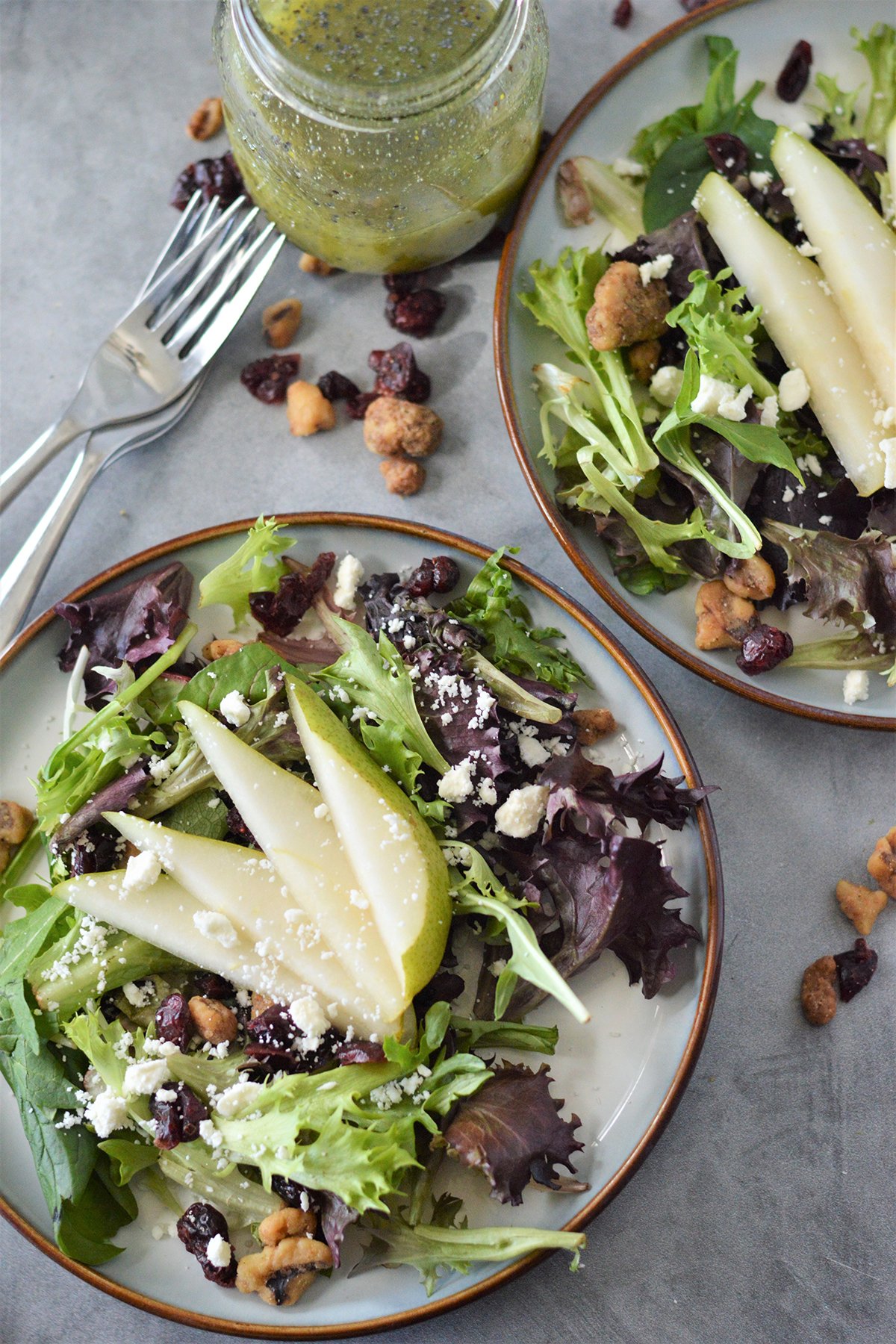 pear salad with dried cranberries, feta cheese and poppy seed dressing on a serving plate