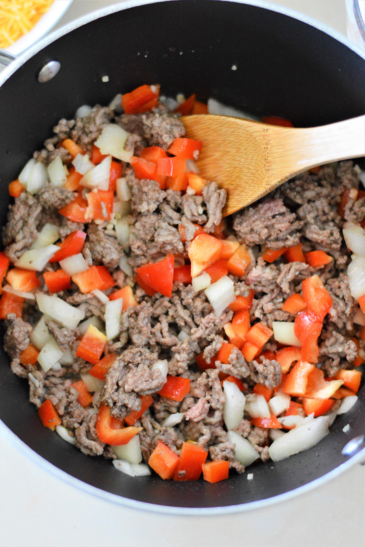 browned ground beef, chopped onions, minced garlic, and bell peppers in a pot