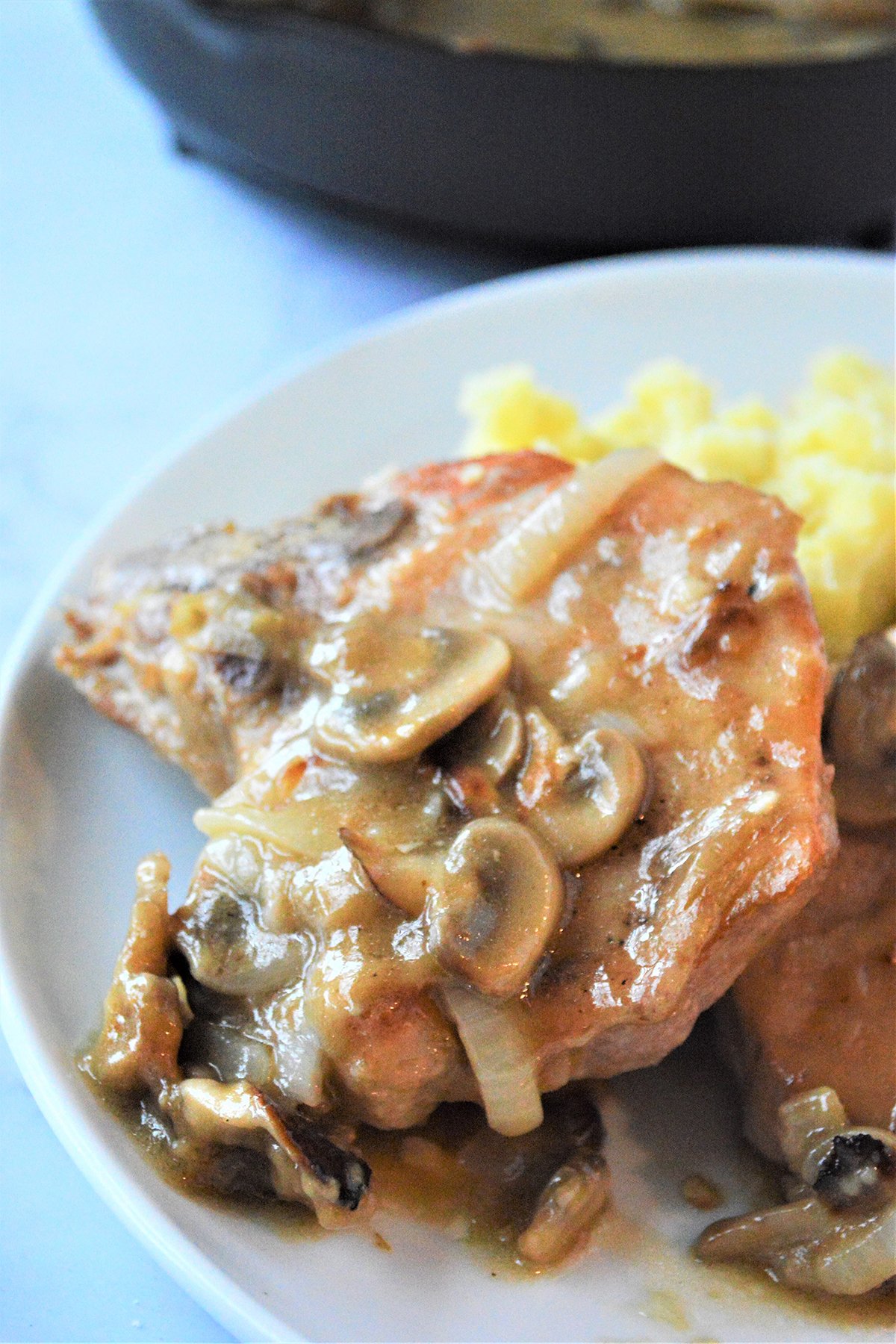 Smothered Pork Chops with Mushroom Gravy with mashed potatoes on a white plate