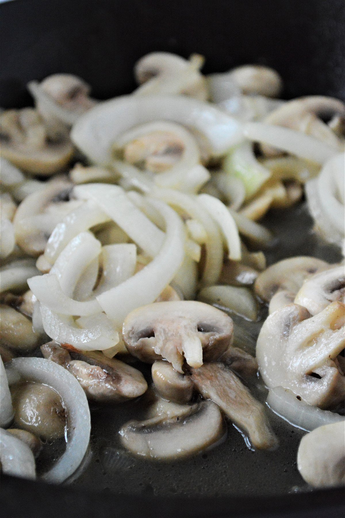 sauteing mushrooms and onions in a cast-iron skillet