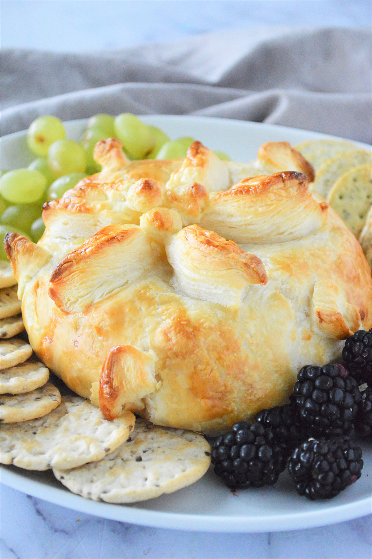 Baked Brie on a white platter with fresh berries and crackers