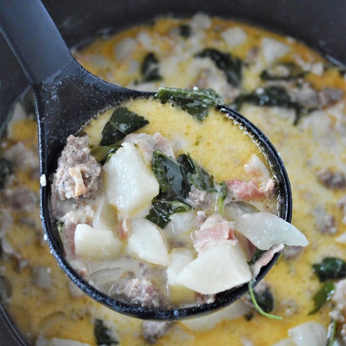 serving zuppa toscana with a ladle from a pot.