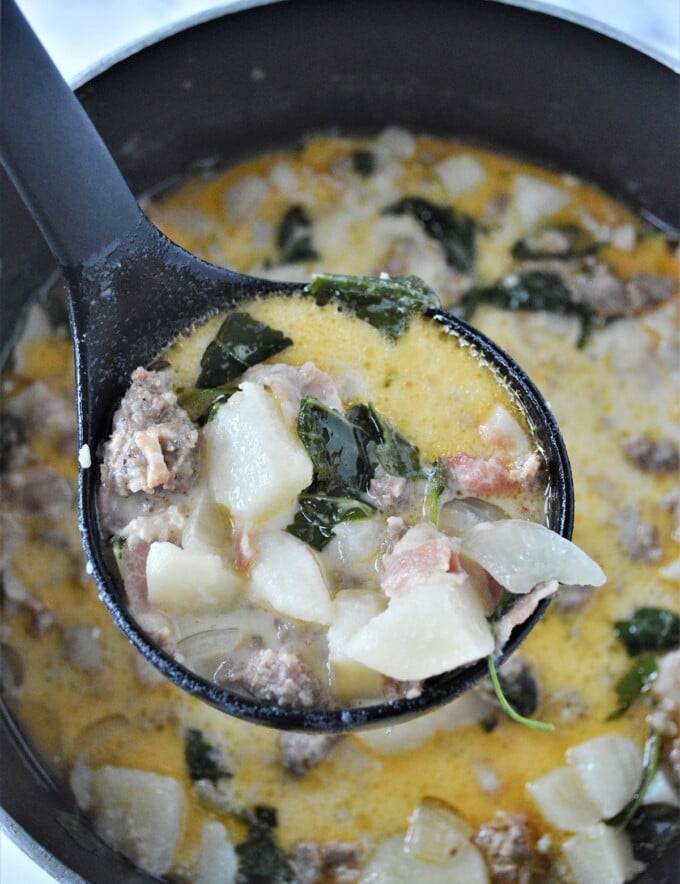 serving zuppa toscana with a ladle from a pot.