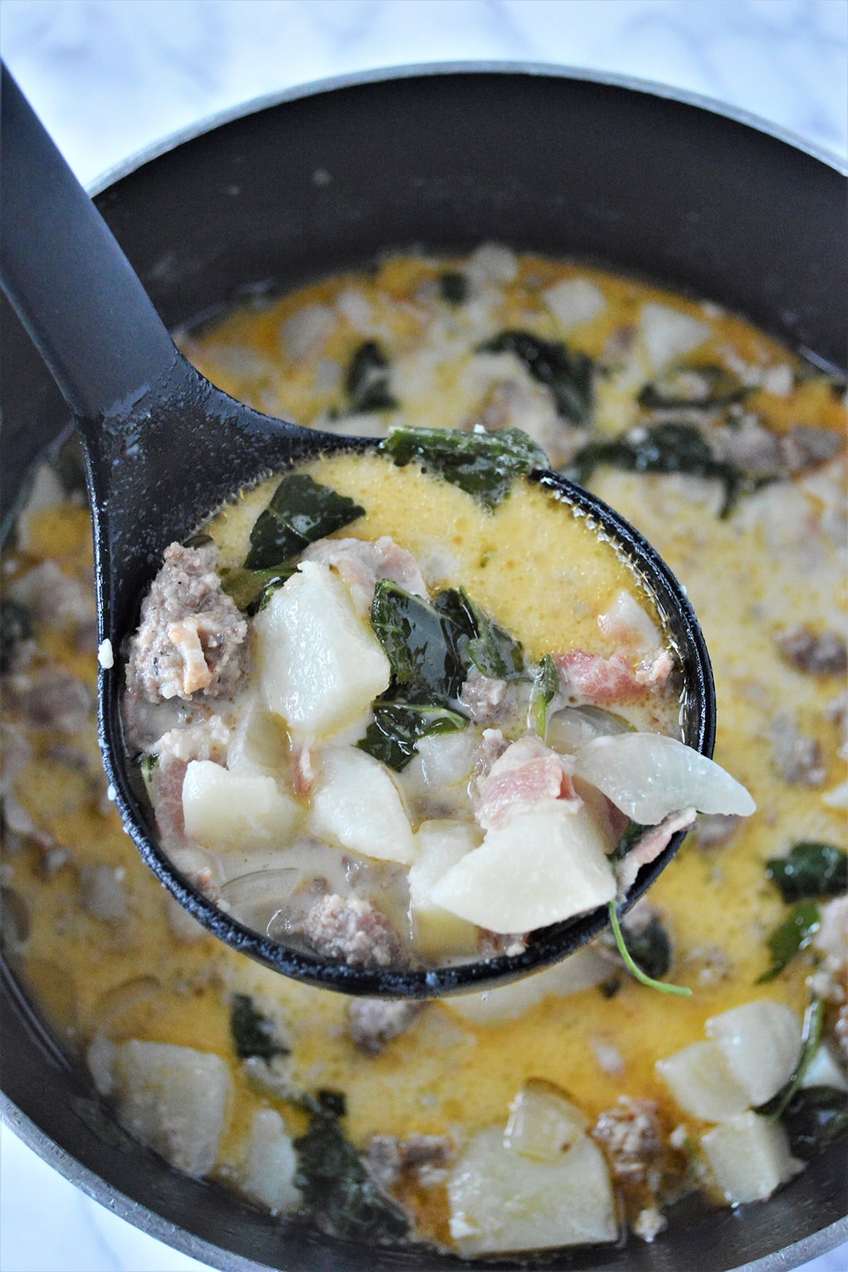 serving zuppa toscana with a ladle from a pot.