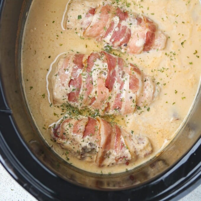 bacon-wrapped chicken cooked in mushroom sauce sauce in a slow cooker.